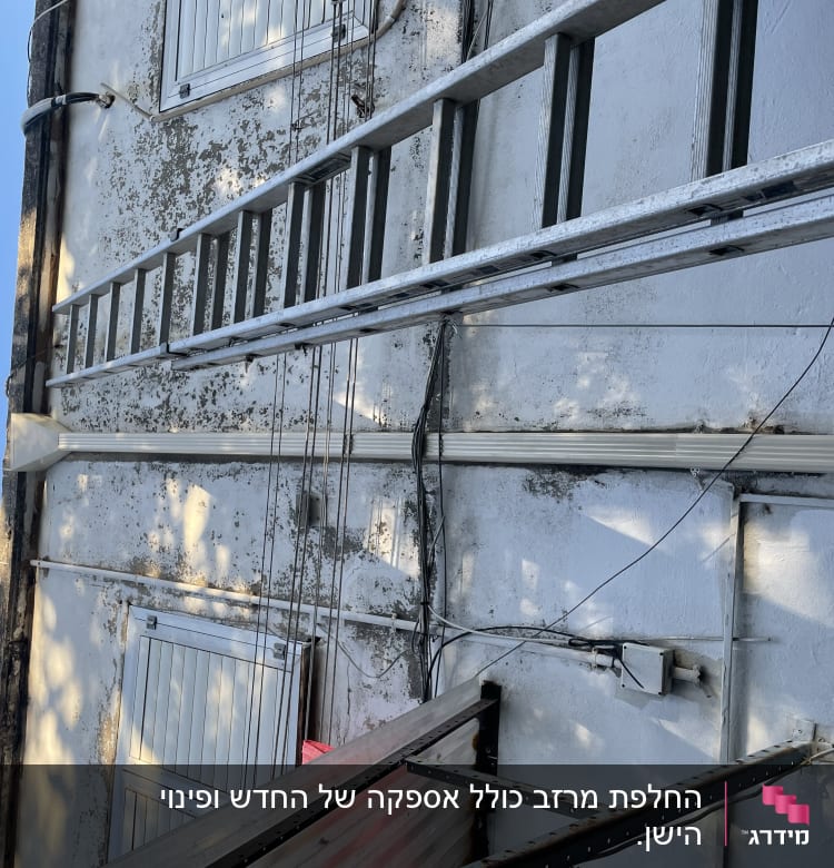 סולם מתכת צמוד לקיר ליד גג